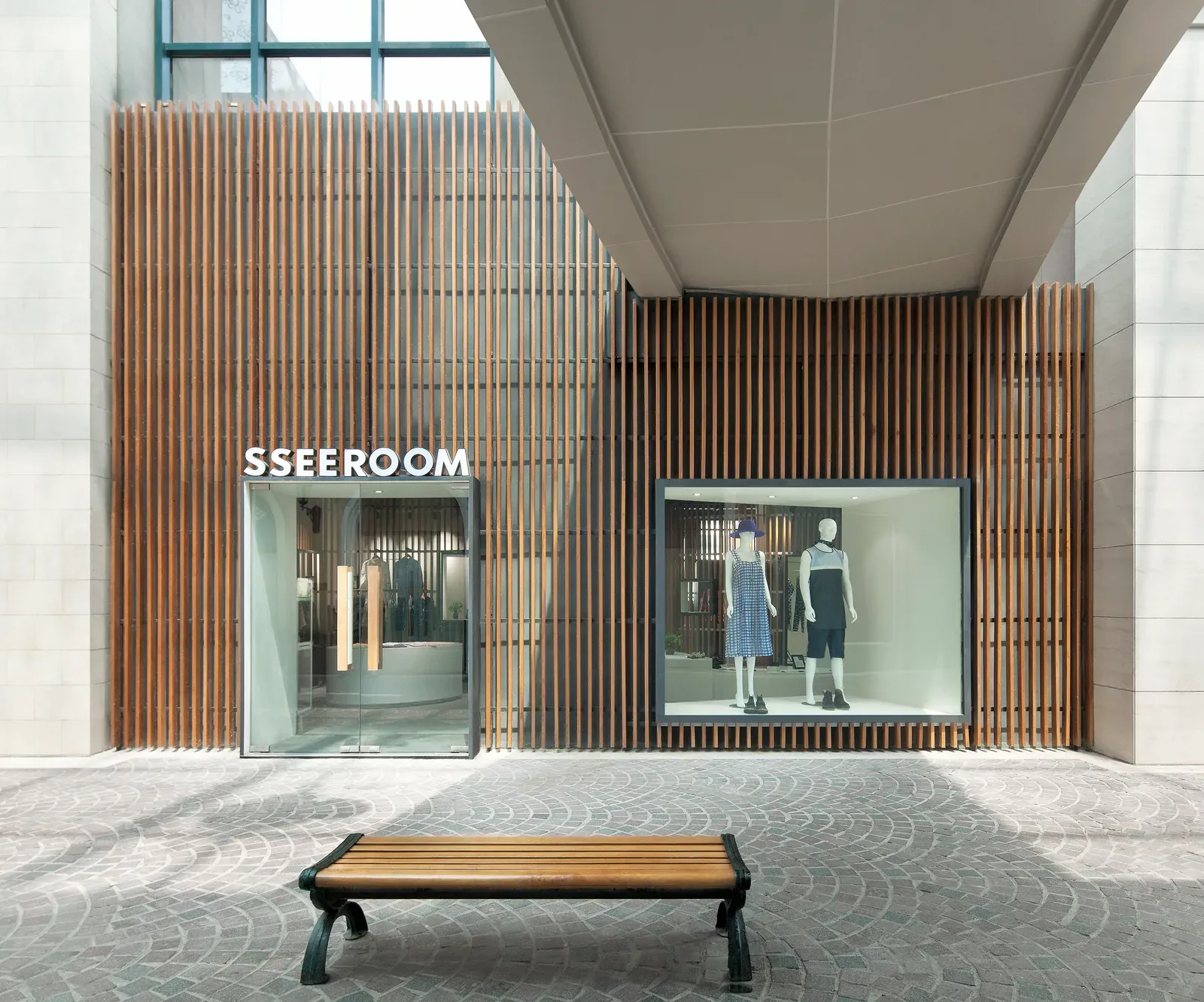 Shopfront with the SSEEROOM sign behind a full-height timber-batten facade