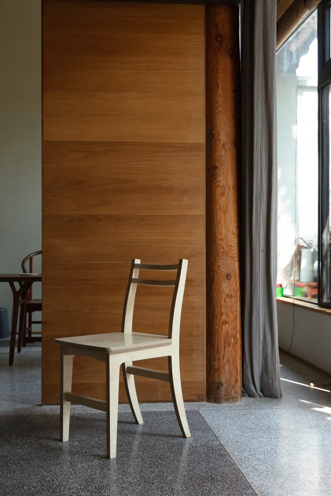 Two-tone dining chair beside a timber wall