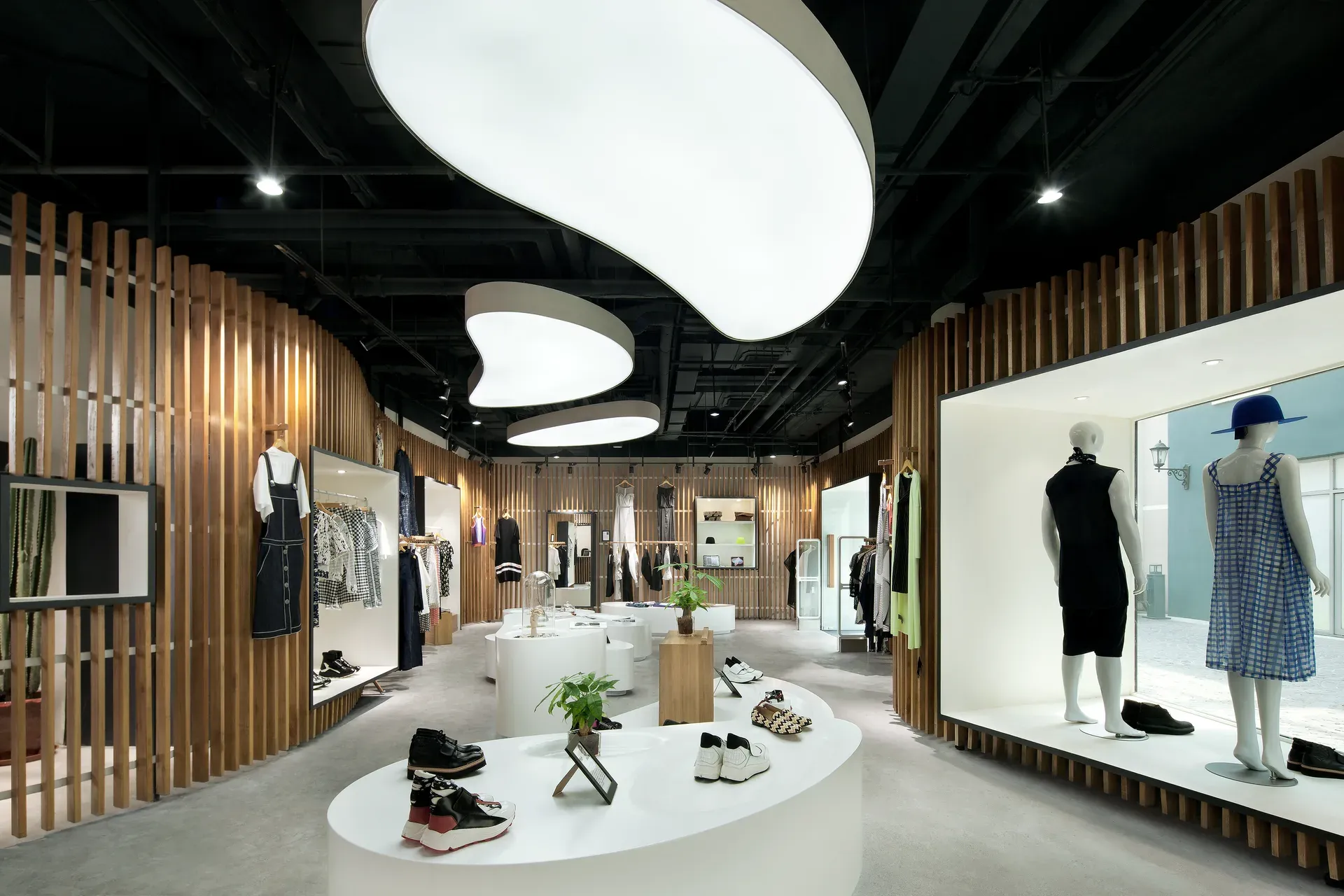 Boutique interior with curved timber-batten walls, white display islands and cloud-shaped light ceilings