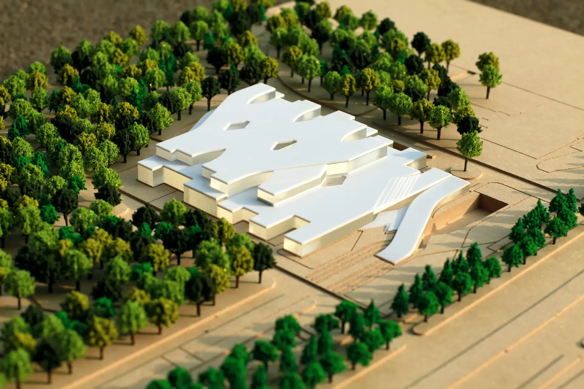 Physical model of the visitor centre, white terraced roofs set among model trees