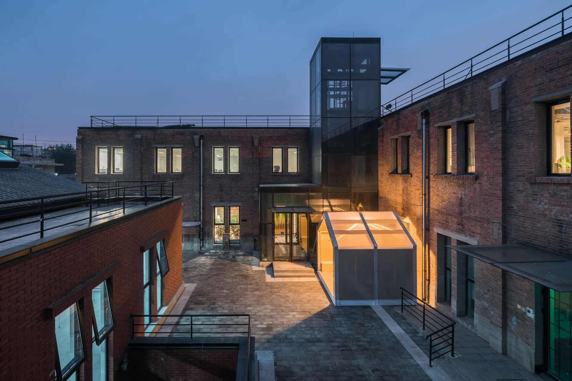 The WikiHouse pavilion lit at dusk in a Dashilar courtyard